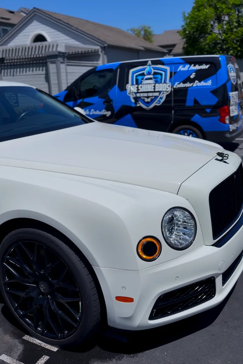 The Shine Bros van parked behind a white Bentley Mulsanne on a driveway.